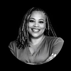 Professional headshot of a woman with braided hair, smiling confidently, wearing a blouse, representing leadership and community engagement in consulting for mission-driven organizations.