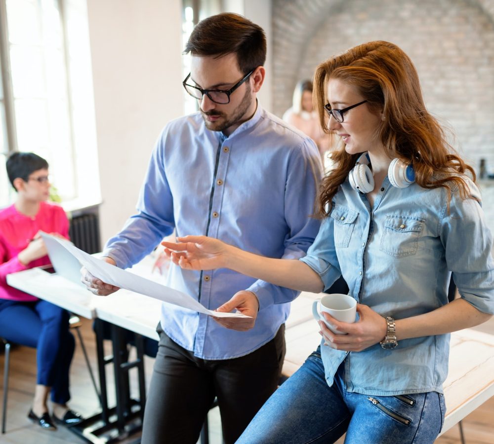 Creative coworkers collaborating in a modern office space, discussing project documents, with a focus on strategy and execution for mission-driven organizations.